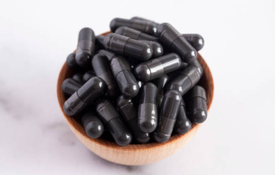 Wooden bowl filled with black胶囊 on a white background